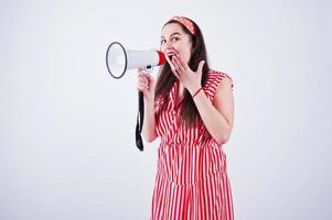 Portrait of a young beautiful woman in red dress talking into megaphone. photo