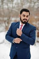 elegante hombre de negocios de barba india en traje posado en el día de invierno al aire libre. foto