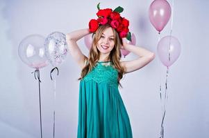 Happy girl in green turqoise dress and wreath with colored balloons isolated on white. Celebrating birthday theme. photo