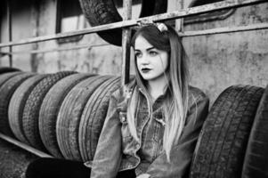 Young hipster girl in jeans jacket and head scarf at tire fitting zone. photo