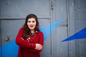 Brunette plus size model at red against colored wall. photo