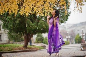 Indian hindu girl at traditional violet saree posed at autumn street. photo