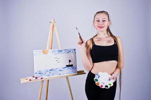 Beautiful woman artist painter with brushes and oil canvas posing in studio isolated on white. photo