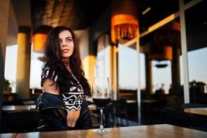 Young curly woman enjoying  her wine in a bar. photo