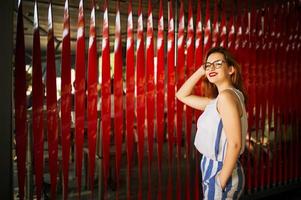 atractiva mujer pelirroja con anteojos posando sobre fondo rojo. foto