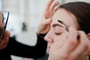 Make up artist work in her beauty visage studio salon. Woman applying by professional make up master. Beauty club concept. photo