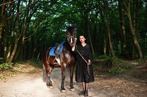 ropa de niña mística en negro con caballo en madera. foto