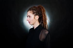 Studio shoot of girl in black with dreads at black background with nimbus. photo