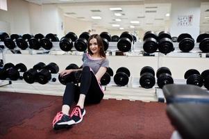 Young brunette sexy slim girl doing workout at gym. photo