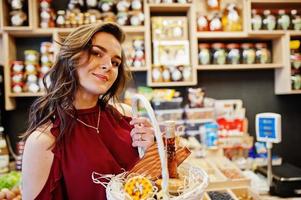 chica de rojo con diferentes productos en la cesta en la tienda de delicatessen. foto