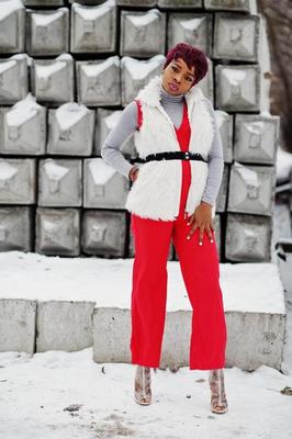 African american woman in red pants and white fur coat jacket