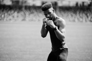 atleta afroamericano boxeador hombre en ropa deportiva haciendo estiramientos en el estadio. foto