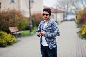 Stylish indian young man at sunglasses wear casual posed outdoor. photo