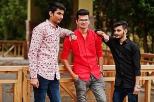Three indian guys students friends walking on street. photo