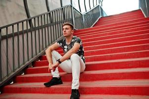 Lifestyle portrait of handsome man posing in red stairs of the city tonnel. photo