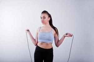 Cheerful attractive young fitness woman in top and black leggings with jump rope isolated over white background. photo