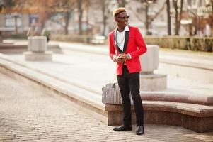 Fashion african american man model at red suit, with highlights hair and handbag posed at street. photo