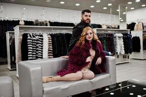 elegancia chica rubia en abrigo de piel y elegante hombre turco en la tienda de abrigos de piel y chaquetas de cuero. foto