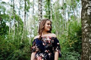 retrato de una joven fabulosa con un bonito vestido con un elegante peinado rizado posando en el bosque o en el parque. foto