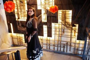 Pretty indian girl in black saree dress posed at restaurant. photo