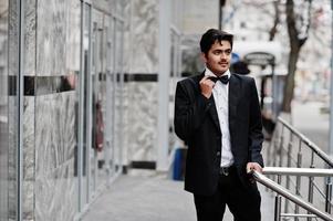 joven indio con traje negro y pajarita posó al aire libre. foto