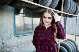 Young hipster girl in checkered shirt at tire fitting zone. photo