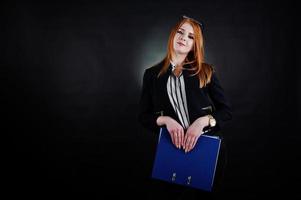 retrato de una mujer de negocios pelirroja con blusa a rayas, gafas y una chaqueta con una carpeta azul. foto