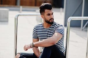 Handsome tall arabian beard man model at stripped shirt posed outdoor. Fashionable arab guy. photo