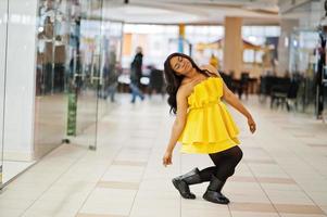 Stylish african american woman at yellow dreess posed at mall. photo