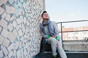 Dreamer stylish macho man in gray suit, scarf and glasses posed on the roof. photo