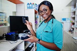 farmacéutico afroamericano que trabaja en la farmacia del hospital. salud africana. trabajo con terminal de pago y tarjeta de crédito. foto