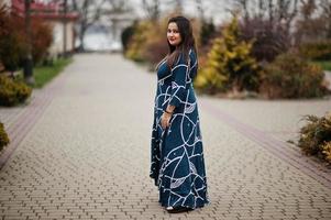 Brunette indian woman in long fashionable dress posed outdoor. photo