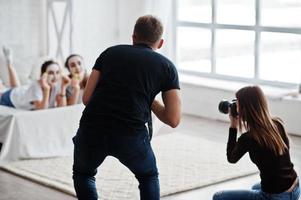 el equipo de dos fotógrafos fotografiando a las gemelas del estudio mientras hacen su propia crema para máscaras. fotógrafo profesional en el trabajo. foto