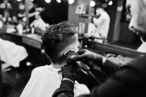 Handsome bearded man at the barbershop, barber at work. photo