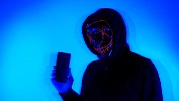 hacker anónimo y mascarilla con smartphone en la mano. foto