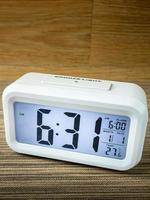 The white alarm clock digital numbers on wood table. photo