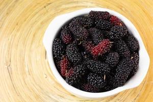 la fruta de morera en un tazón blanco sobre una mesa de madera. foto