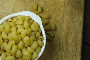 Macaroni raw in white bowl on wood table photo