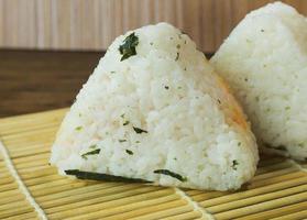 la comida japonesa onigiri arroz blanco formado en formas triangulares o cilíndricas y, a menudo, envuelto en nori. foto