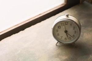 alarma de reloj vintage blanco cerca de la luz de la ventana. foto