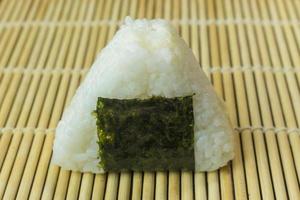 The Japanese food Onigiri  white rice formed into triangular or cylindrical shapes and often wrapped in nori. photo