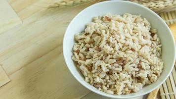 BROWN RICE in white bowl on wood table for health food content. photo