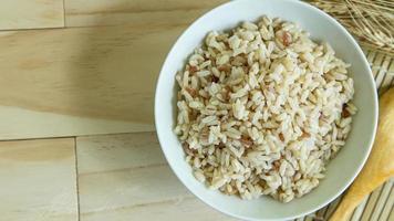 BROWN RICE in white bowl on wood table for health food content. photo