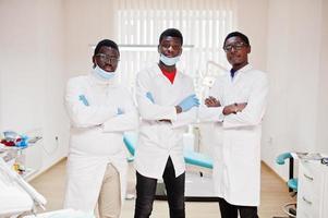 tres médicos varones afroamericanos con los brazos cruzados en la clínica dental. foto