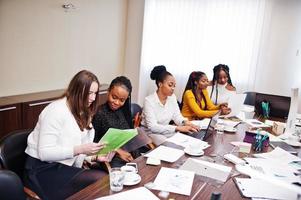 Multiracial women colleagues, crew of divercity female partners in office sit at the table. photo