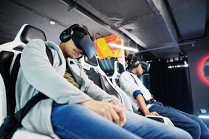 Two young indian people having fun with a new technology of a vr headset at virtual reality simulator. photo