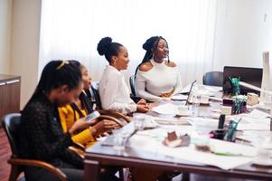 African american women colleagues, crew of divercity female partners in office sit at the table. photo