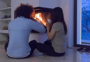 happy multiethnic couple sitting in front of fireplace photo