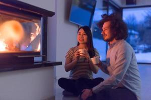 happy multiethnic couple sitting in front of fireplace photo