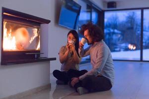 happy multiethnic couple sitting in front of fireplace photo